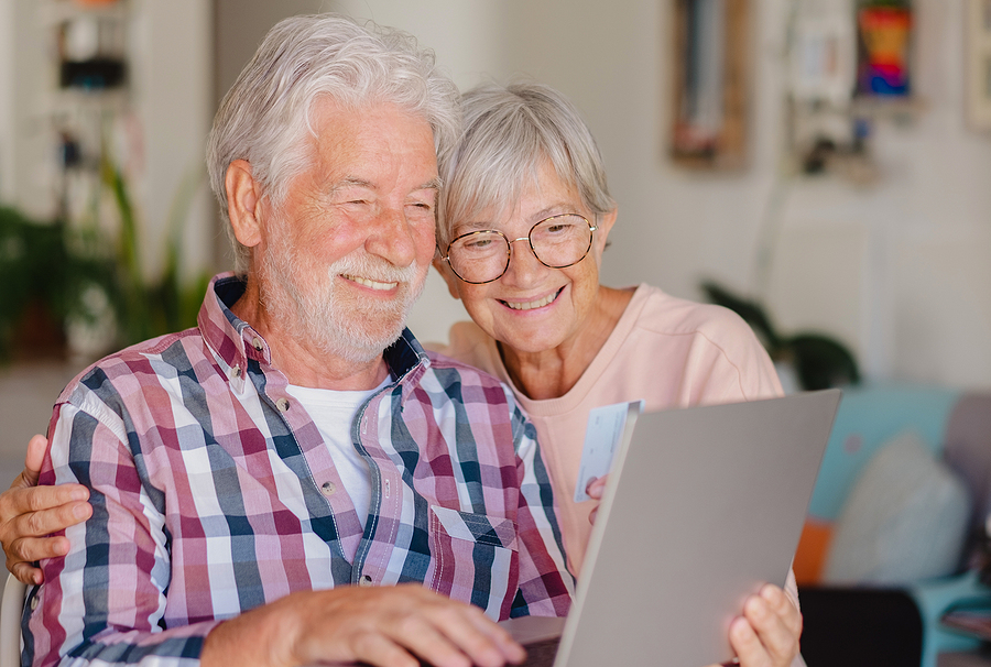 Portrait Of Happy Modern Elderly Couple Browsing Together On Laptop