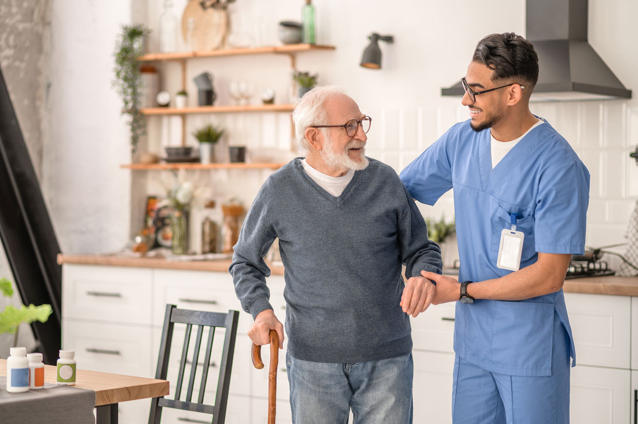 A caregiver helping a senior man to stand up