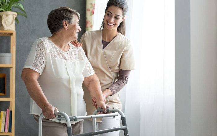 Happy caregiver helps an elderly woman with a walker