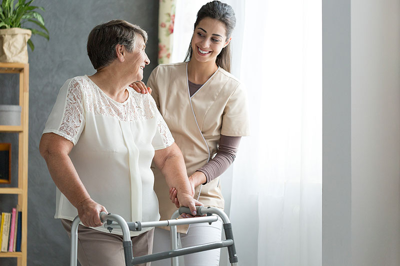 cbah-blog-6-02-2025 Happy caregiver helps an elderly woman with a walker